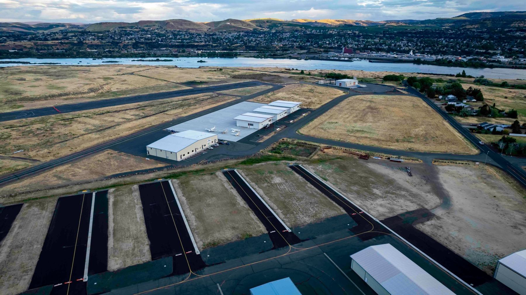 Aerial view of Columbia Gorge Regional Airport with the Columbia River and The Dalles, Oregon behind it